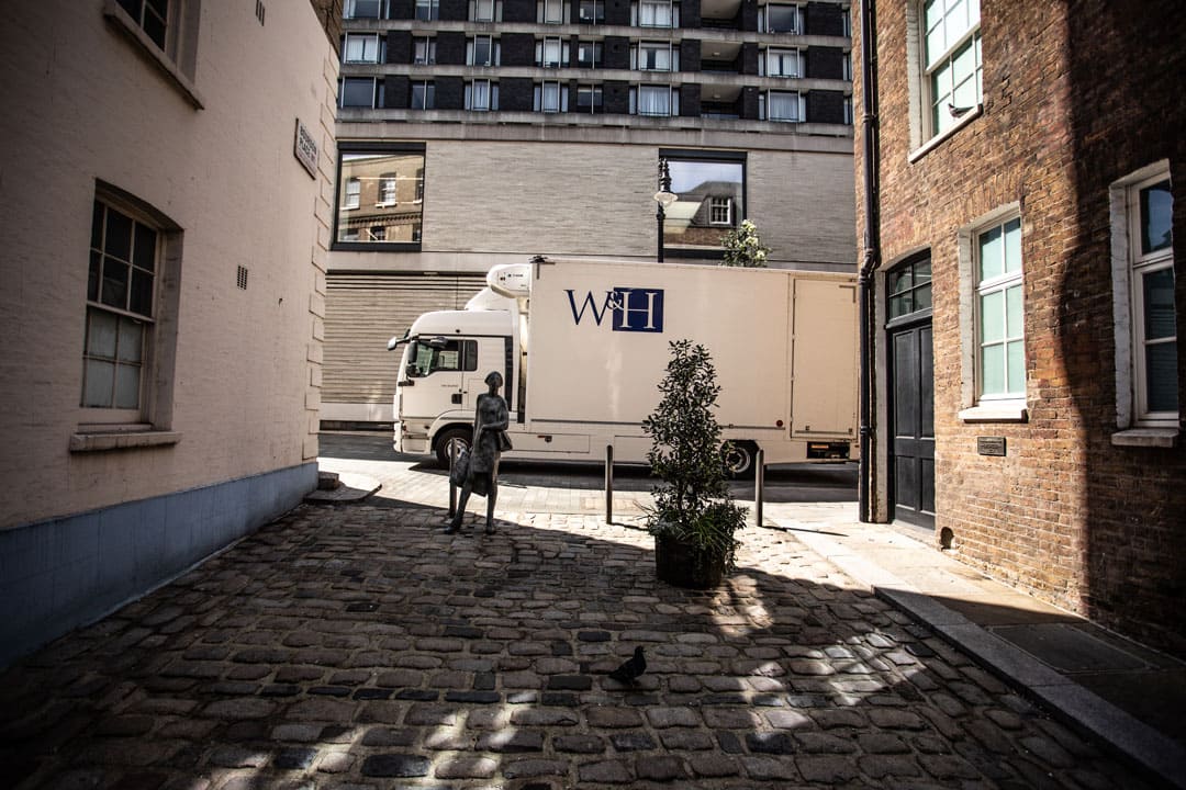 Williams and Hill truck passing cobbled street with statue